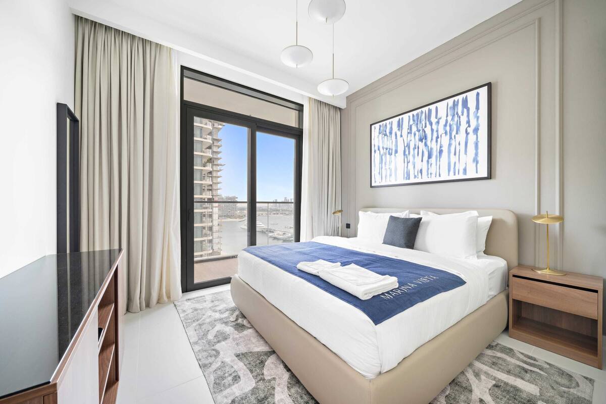 Habitación de hotel con una cama grande, televisión, escritorio y vistas a la ciudad por la ventana.