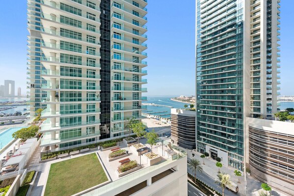 A high-rise building with multiple balconies, a rooftop garden, and a view of the sea.
