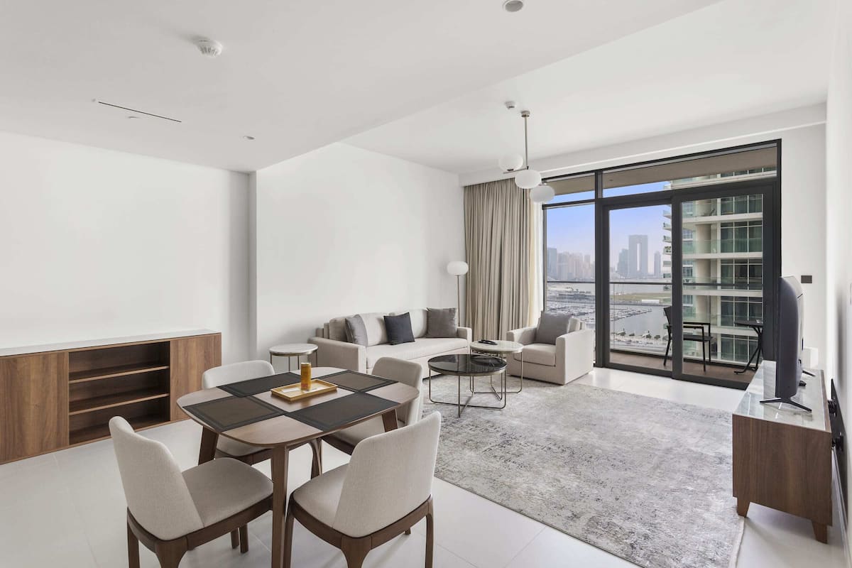 Una sala de estar moderna con comedor, un conjunto de sofás y un amplio ventanal con vista a la ciudad.