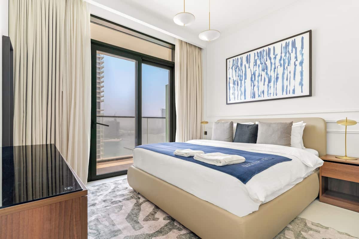 Una habitación de hotel con una cama grande, televisión, balcón y un cuadro en la pared.