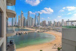 A high-rise building with a view of a coastal cityscape, including a marina and a sandy beach.