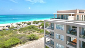 Ein mehrstöckiges Hotel mit Balkonen mit Blick auf Strand und Meer.