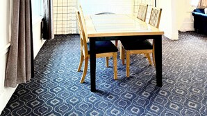 Un espace repas avec une table et des chaises, un coin cuisine avec une fenêtre et une moquette à motifs.