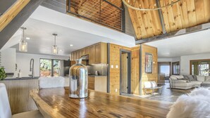 Una cocina moderna con armarios de madera, una gran mesa de comedor de madera y una lámpara colgante.