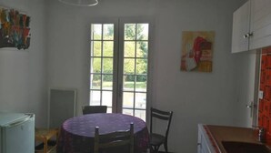 A kitchen with a round table, chairs, a window, and cabinets. - La Villa Champenoise (Pierry)