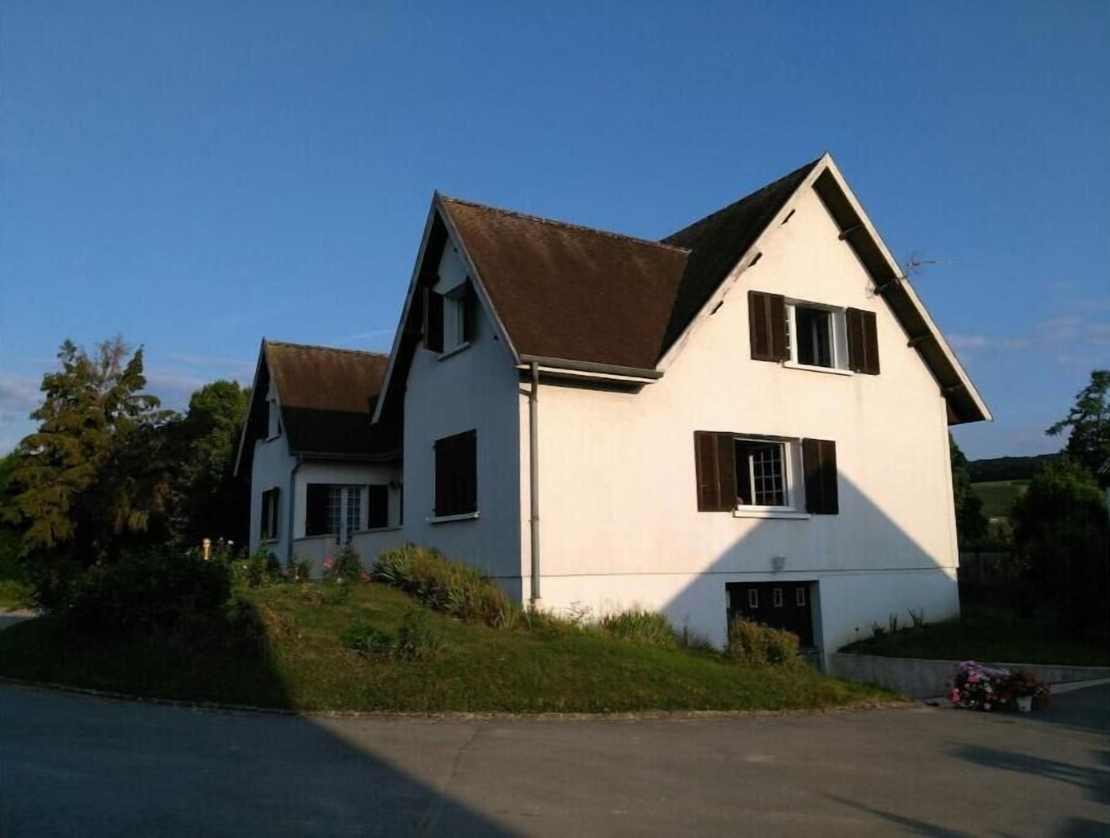 Uma casa de dois andares com telhado empena e porta da frente.