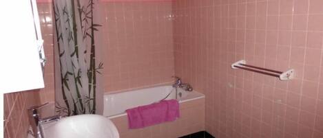 A bathroom with a sink, a bathtub, and a shower curtain.