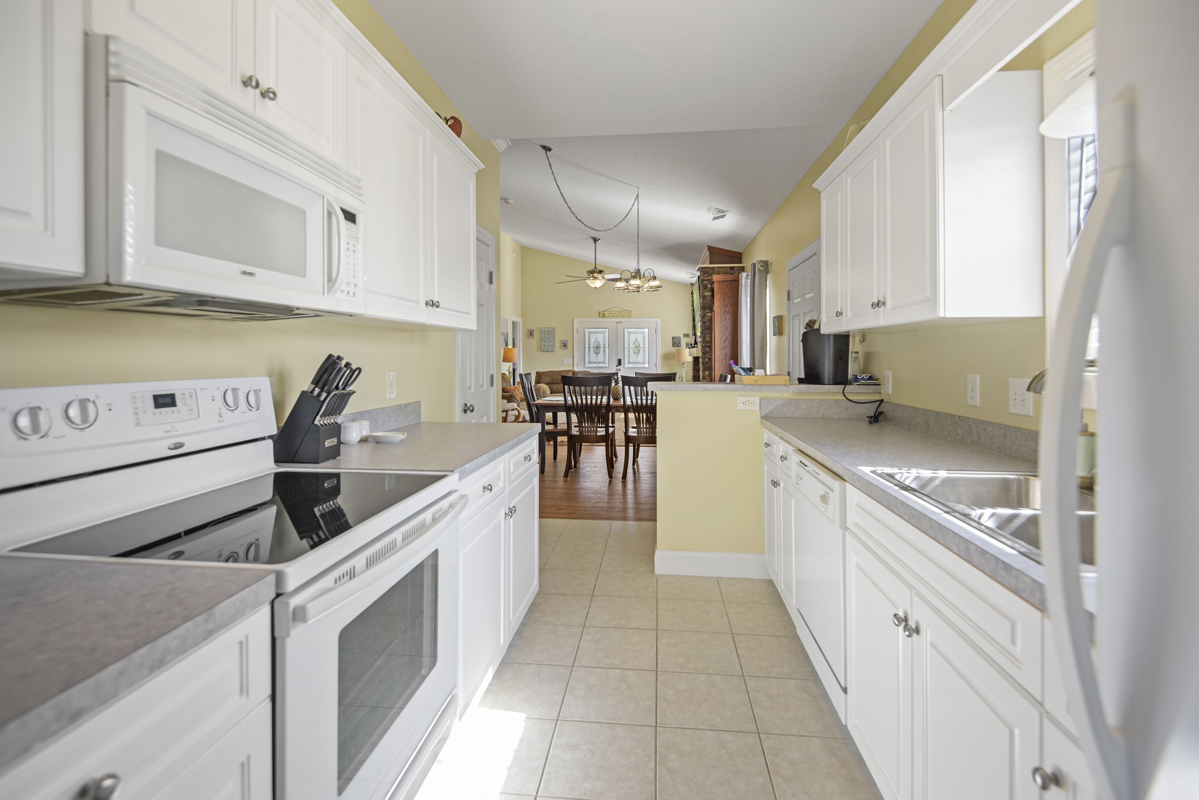 A kitchen with white cabinets, a stove, and a dining area in the background.