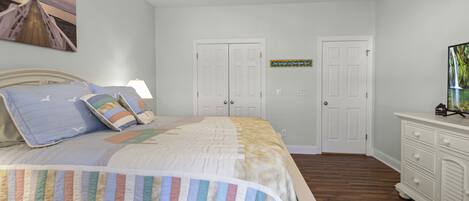 A bedroom with a bed, two doors, a dresser, and a ceiling fan.