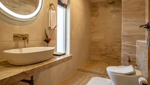 A modern bathroom with a large oval sink, a toilet, and a shower.