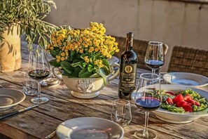 Una mesa de madera preparada para una comida, con una botella de Colletto, una ensalada y copas de vino vacías.