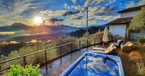 A hot tub on a wooden deck with a view of mountains and a sunset. - Tuscany, amazing view, private jacuuzi (Coreglia Anteminelli)