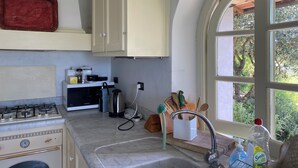 A kitchen with a gas stove, microwave, sink, and wooden countertop.