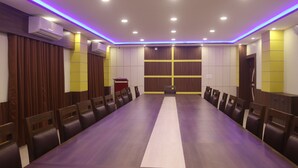 A conference room with a long table and chairs, air conditioning units, and a podium. - Janaki Star Hotel (Janakpur)