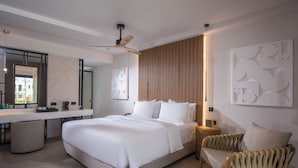 A modern hotel room with a large bed, a sitting area with a chair, a desk with a mirror, and a view of the outside. - Noble Hotel Suites - Adults Only (Hersonissos)