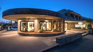 A modern hotel entrance with a curved facade, a stone wall, and a sign reading "Noble Hotel Suites". - Noble Hotel Suites - Adults Only (Hersonissos)