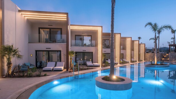 A modern hotel with a pool area, including lounge chairs and a well-lit pool. - Noble Hotel Suites - Adults Only (Hersonissos)