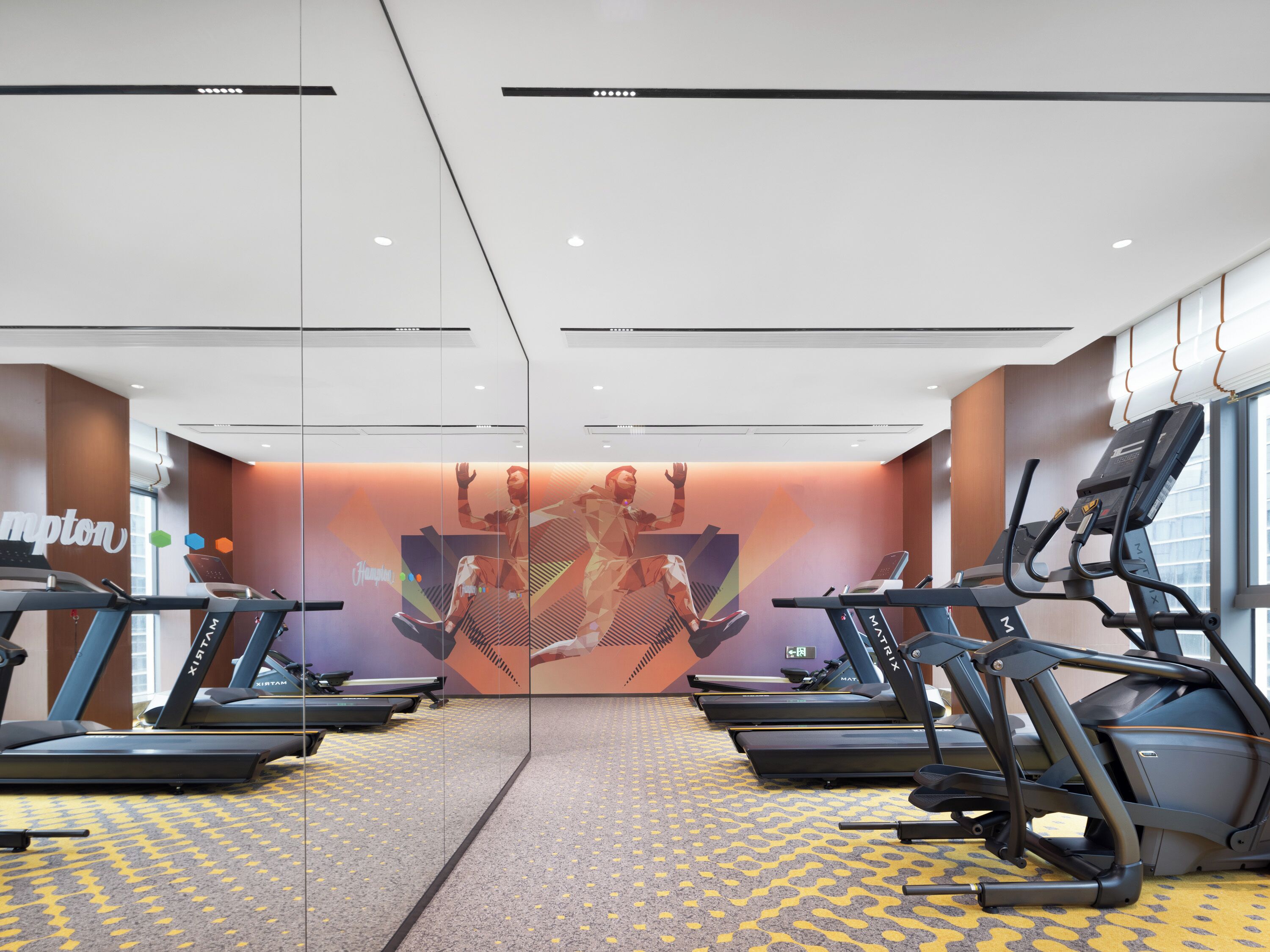 A gym with treadmills, mirrored walls, and a motivational mural.