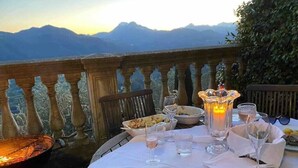 A table set outdoors with a view of mountains, a candle, and a grill.