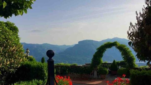 A pool surrounded by lush greenery and a mountain backdrop.