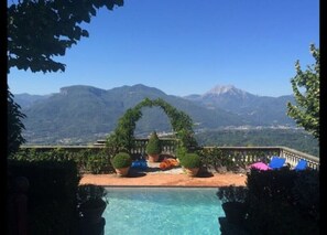 A pool area with a view of mountains, surrounded by potted plants and outdoor furniture. - Villa Paradiso,stunning views+gardens,heated pool (Coreglia Anteminelli)
