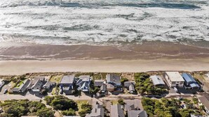 An aerial view of a coastal residential area with houses adjacent to a beach and ocean. - Unreal Panoramic Oceanfront and Beach Views, Hot Tub, New Game Room, Fire-table, 1/2 Mile to Town (Rockaway Beach)