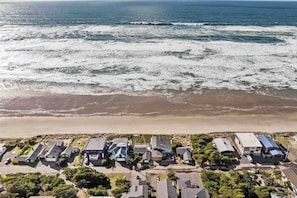 Vista aérea de una zona residencial costera con casas junto a una playa y el océano.