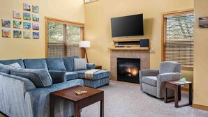 A living room with a sectional sofa, a fireplace, a television, and artwork on the walls. - Fantastic Single Level Shorepines Village Home, Steps From Beach and Ocean, 1/4 Mile to Kiwanda (Cloverdale)