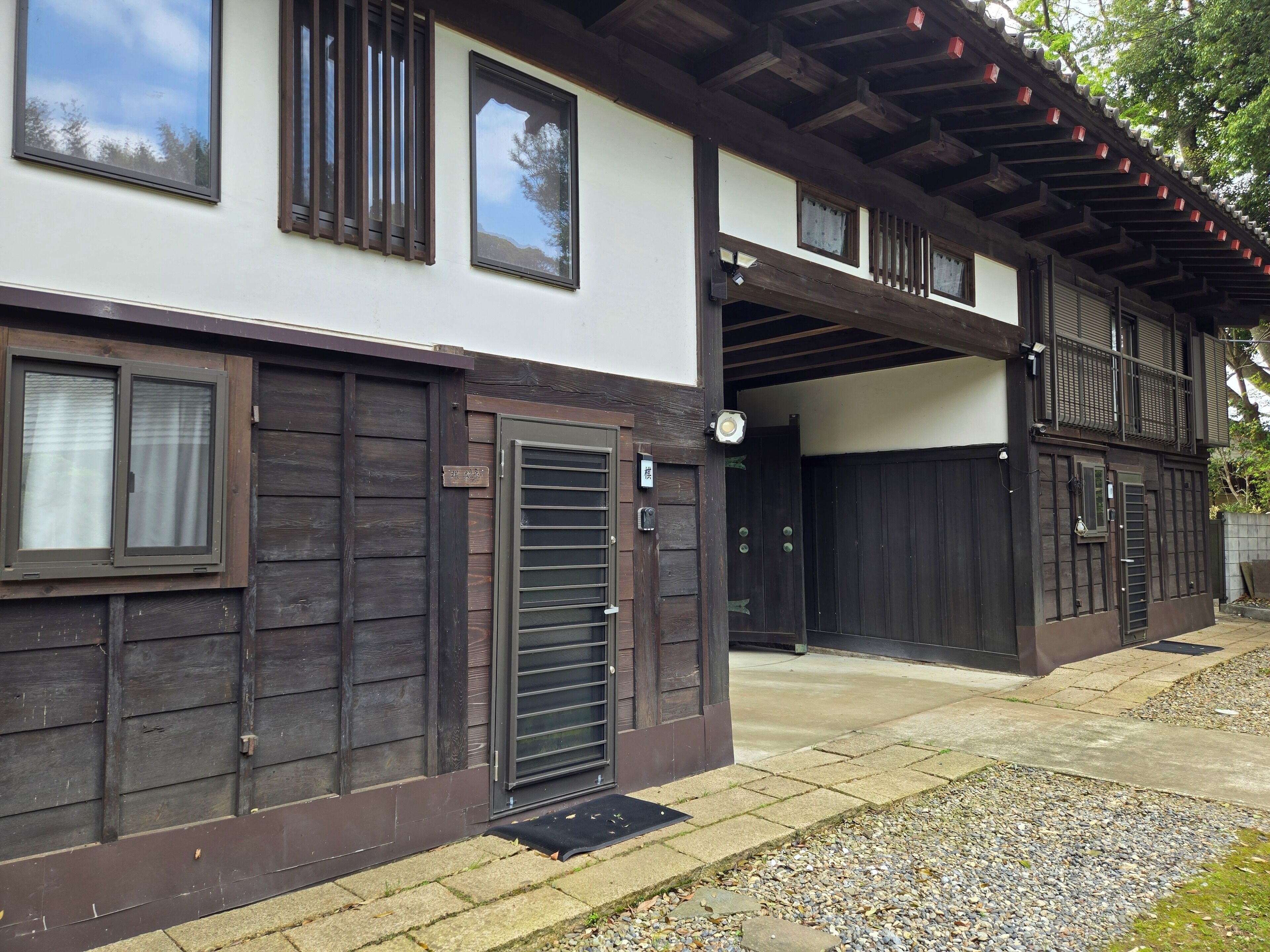 A traditional Japanese-style building with a wooden exterior, a covered entrance, and a small garden area with gravel and stepping stones.