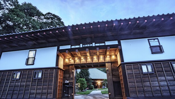 A building with a wooden facade, a covered entrance, and a well-maintained garden. - One Night One View One Destiny (Yotsukaido)