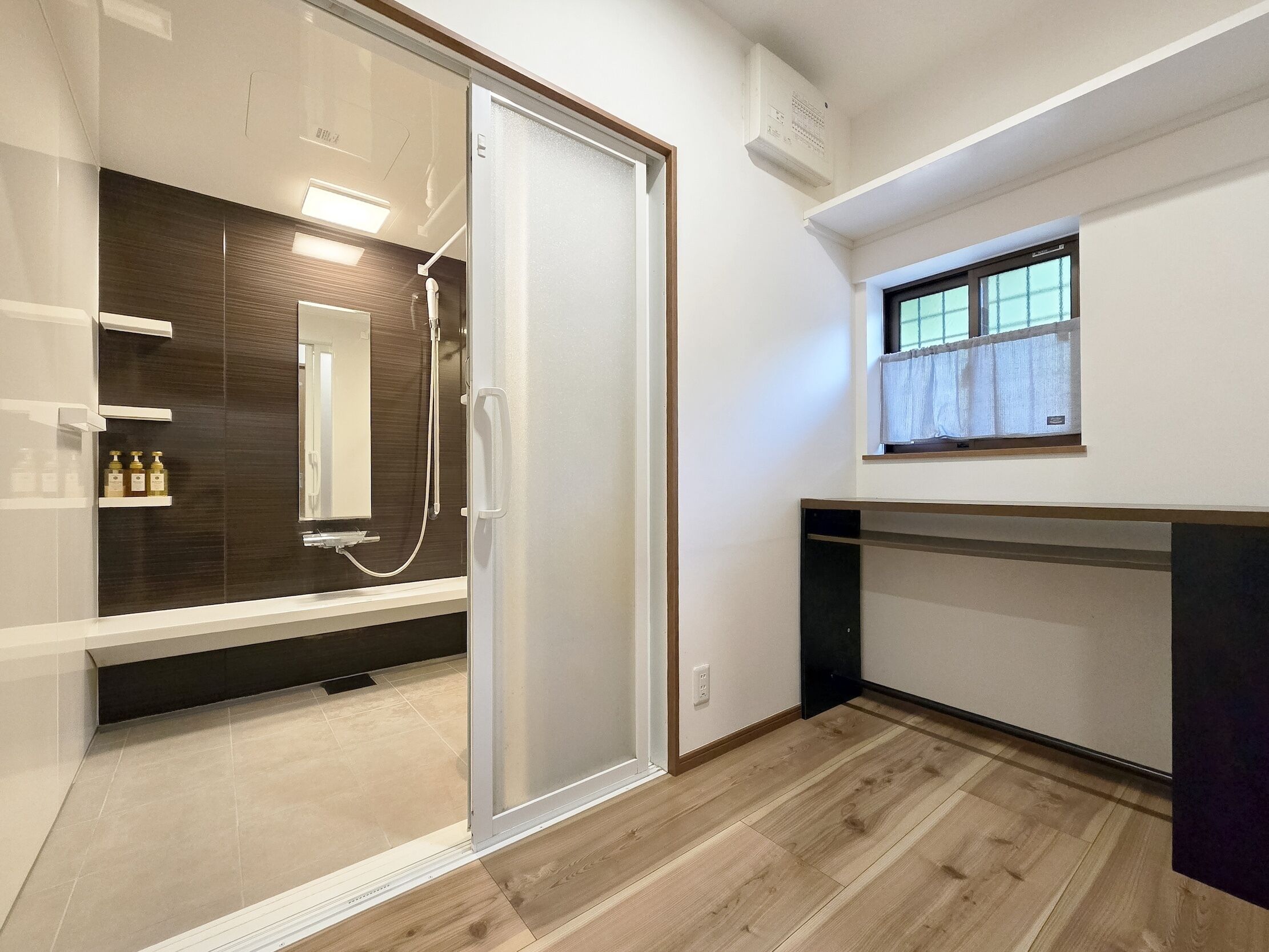 A modern bathroom with a glass shower enclosure, a vanity with a mirror, and a window above the sink.