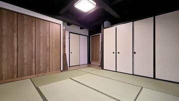 A traditional Japanese room with tatami flooring, wooden sliding doors, and a ceiling light fixture.