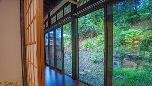 A traditional Japanese room with tatami flooring, sliding doors, and a view of a lush garden. - One Night One View One Destiny (Yotsukaido)