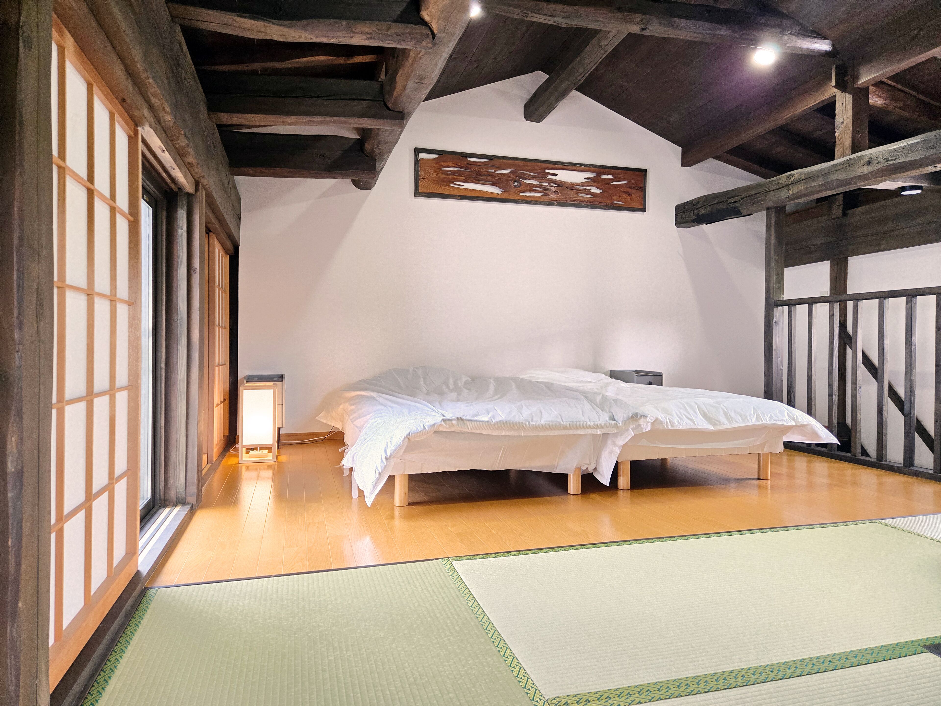 Una habitación tradicional japonesa con suelo de tatami, una cama de madera baja y una puerta corredera shoji.
