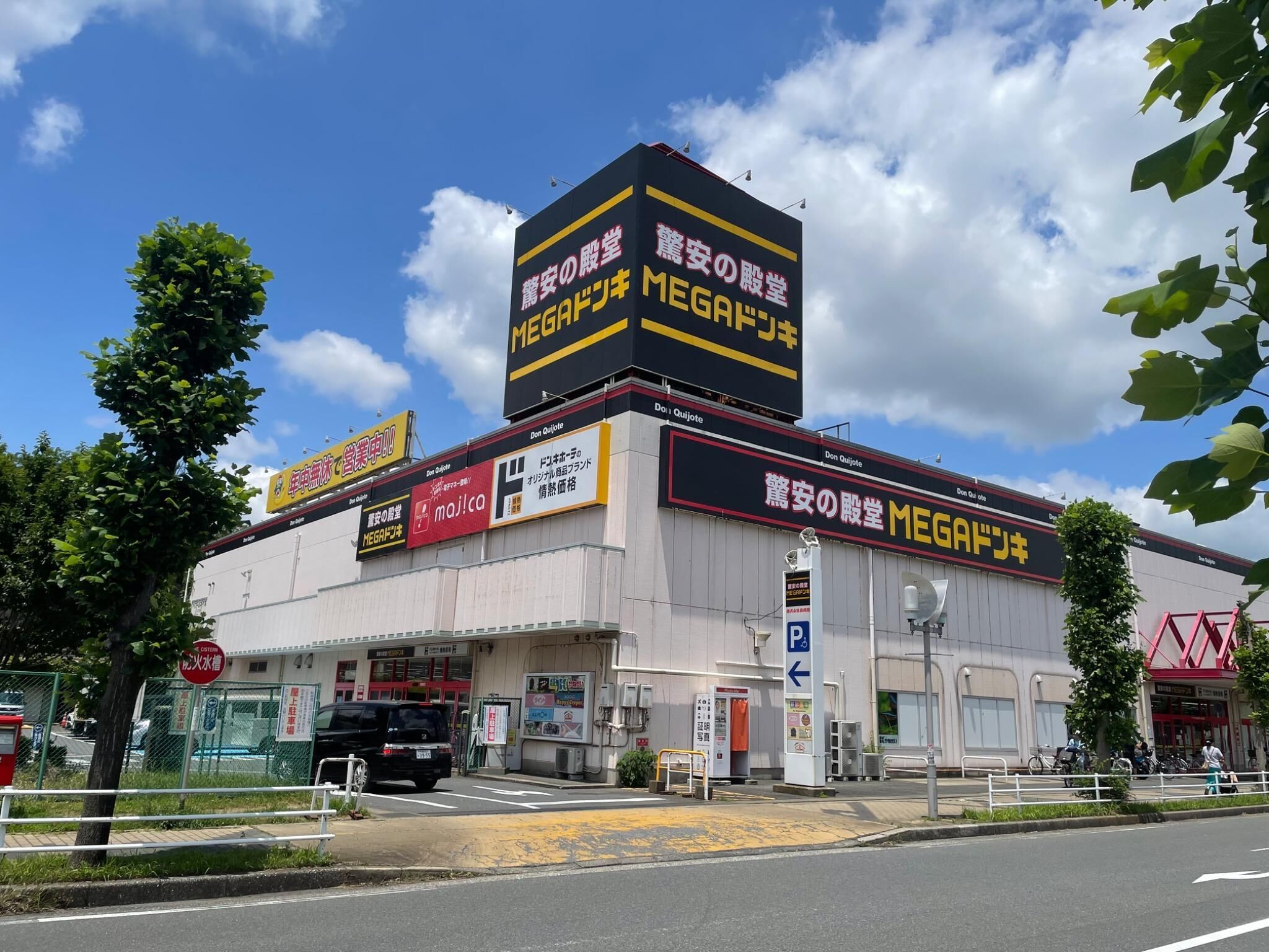 A commercial building with multiple signs, including a prominent 'MEGA' sign, and a parking sign indicating a parking area.