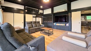 A spacious living room with a high ceiling, a sofa, a coffee table, and a television. - One Night One View One Destiny (Yotsukaido)