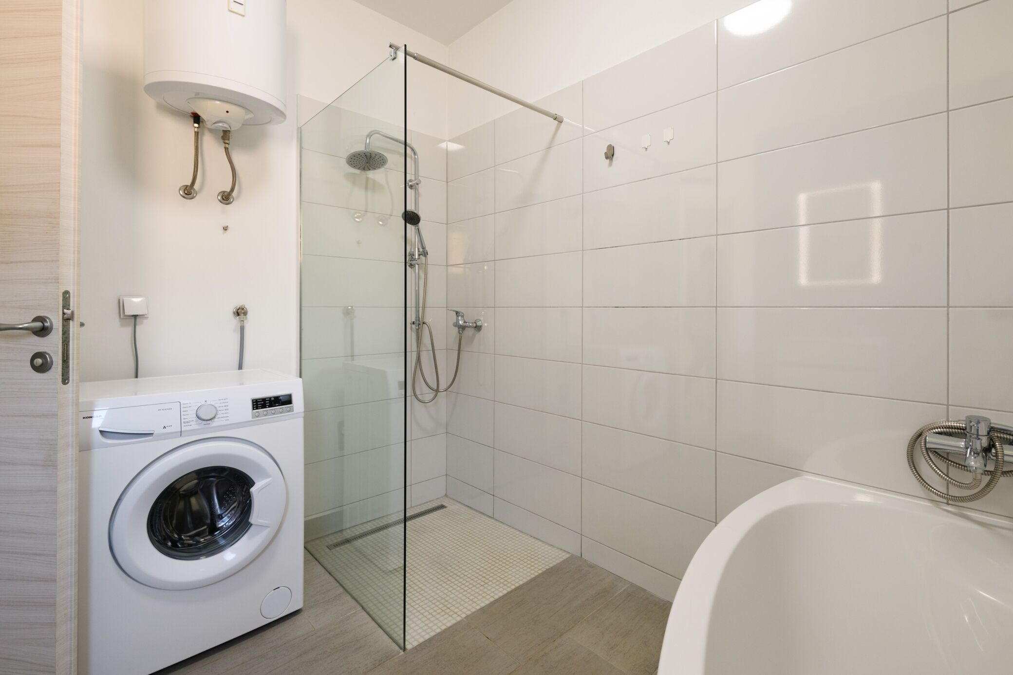 Un bagno moderno con doccia vetro, lavatrice indipendente e vasca da bagno.