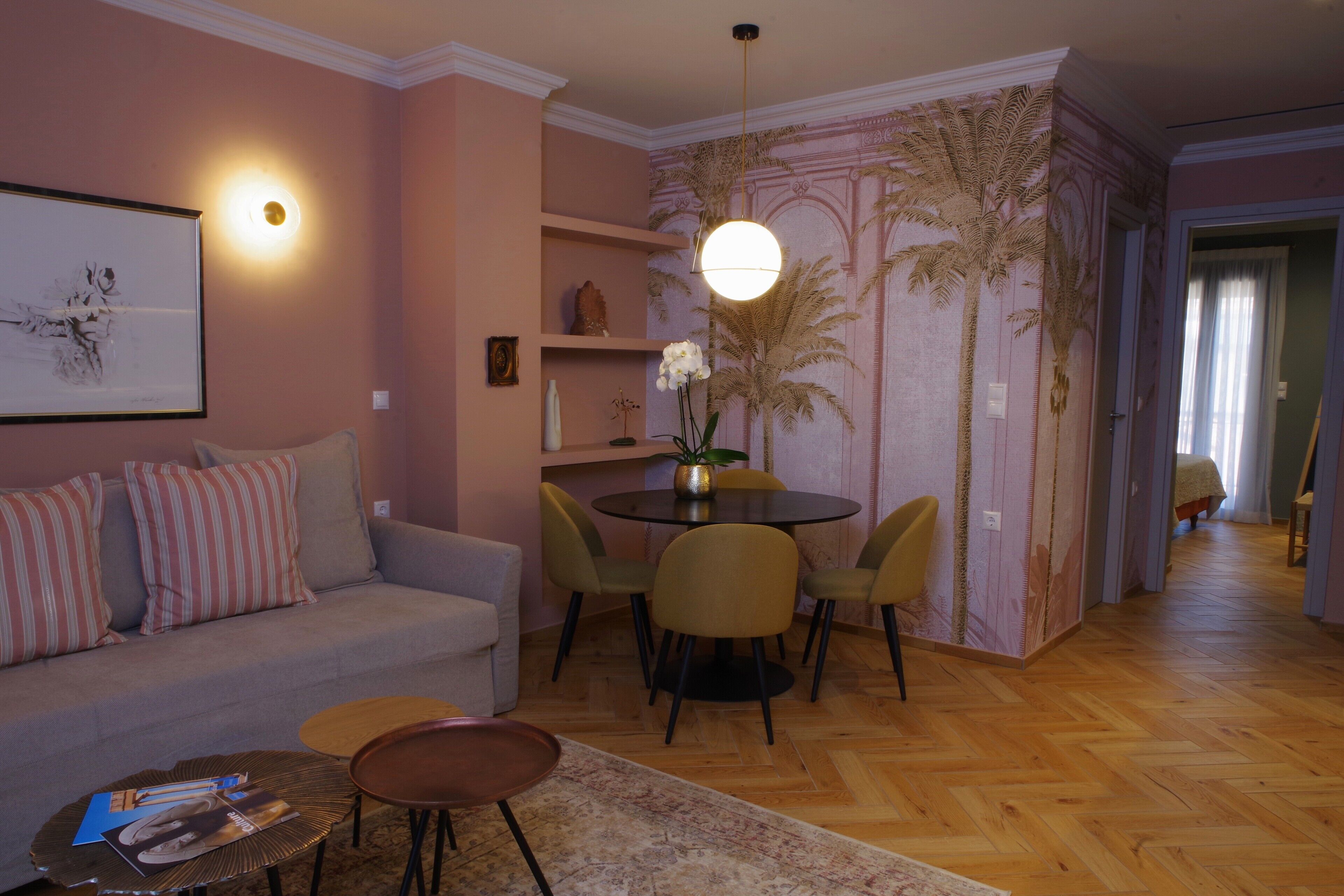 Una sala de estar con sofá, sillas, una mesita de centro, una mesa de comedor y una pared con un mural de una palmera.