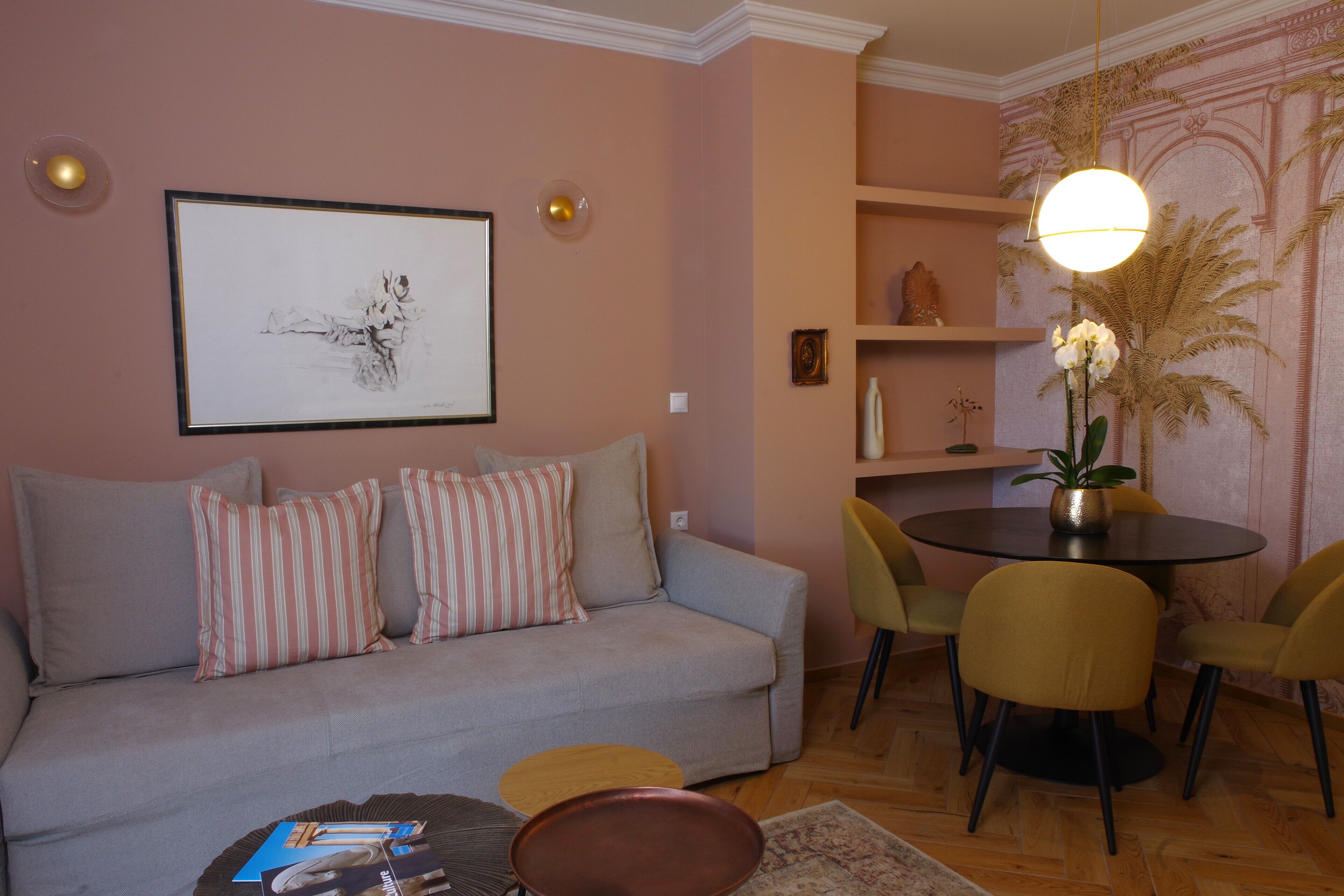 Ein Wohnzimmer mit einer Couch, Sesseln, einem Couchtisch und einem Esstisch mit Stühlen.