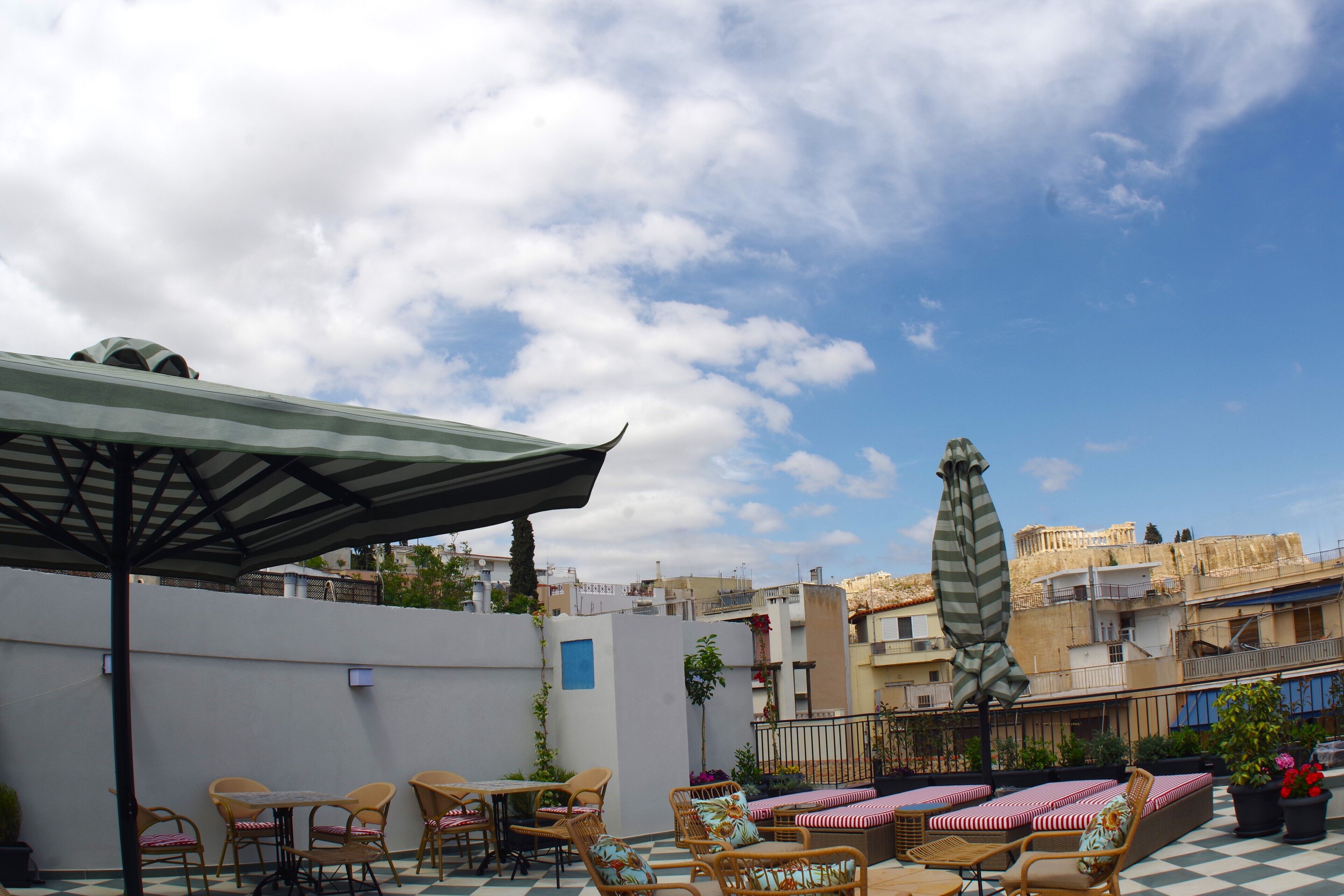 A rooftop terrace with outdoor seating, including wicker chairs and a table, and a checkered floor.