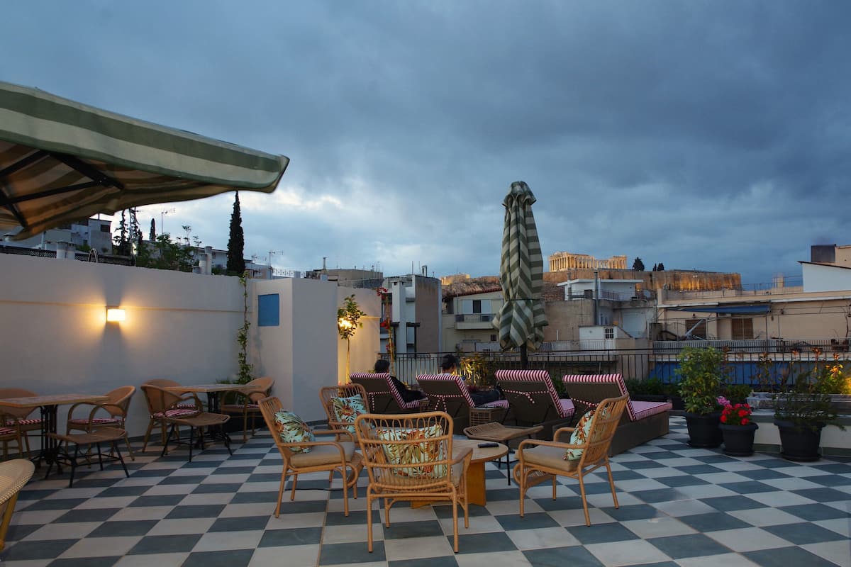 A rooftop terrace with checkered flooring, wicker furniture, and potted plants.