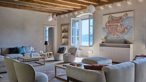 Een ruime woonkamer met een hoge plafond, een groot raam en een kaart aan de muur.