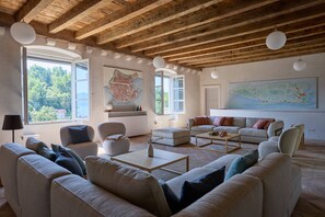 Un salón amplio con techo de madera alta, ventanas grandes y un mapa en la pared.