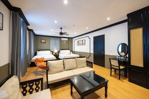 A modern hotel room with a sofa, a small table, a chair, a bed, a ceiling fan, and a door with a mirror. - Sunset Bay Retreat Hotel  (Phu Quoc)