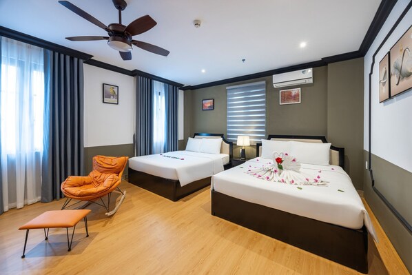 A hotel room with two beds, a rocking chair, a small table, and a ceiling fan.