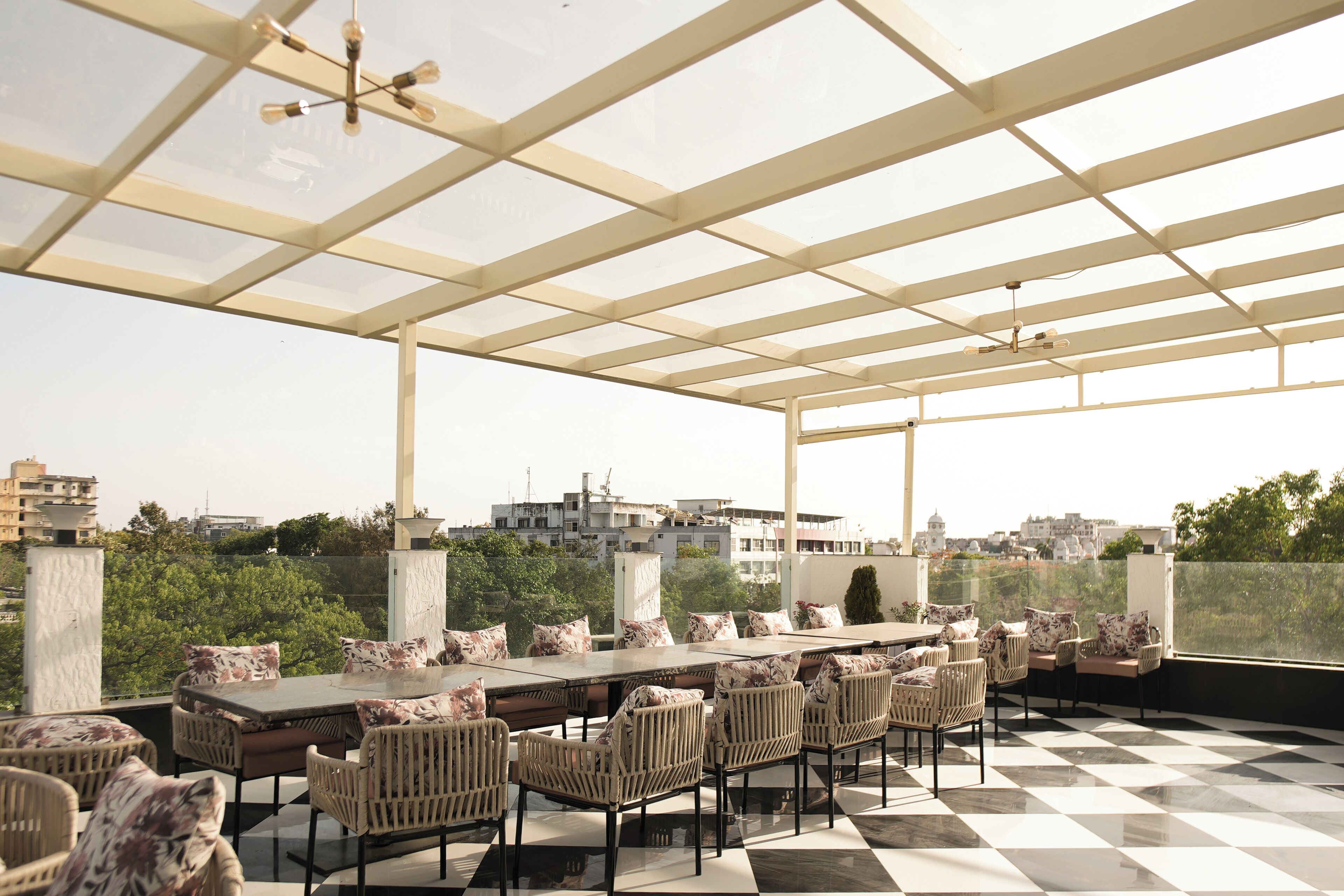 A covered outdoor seating area with a checkered floor, a long table, and wicker chairs.