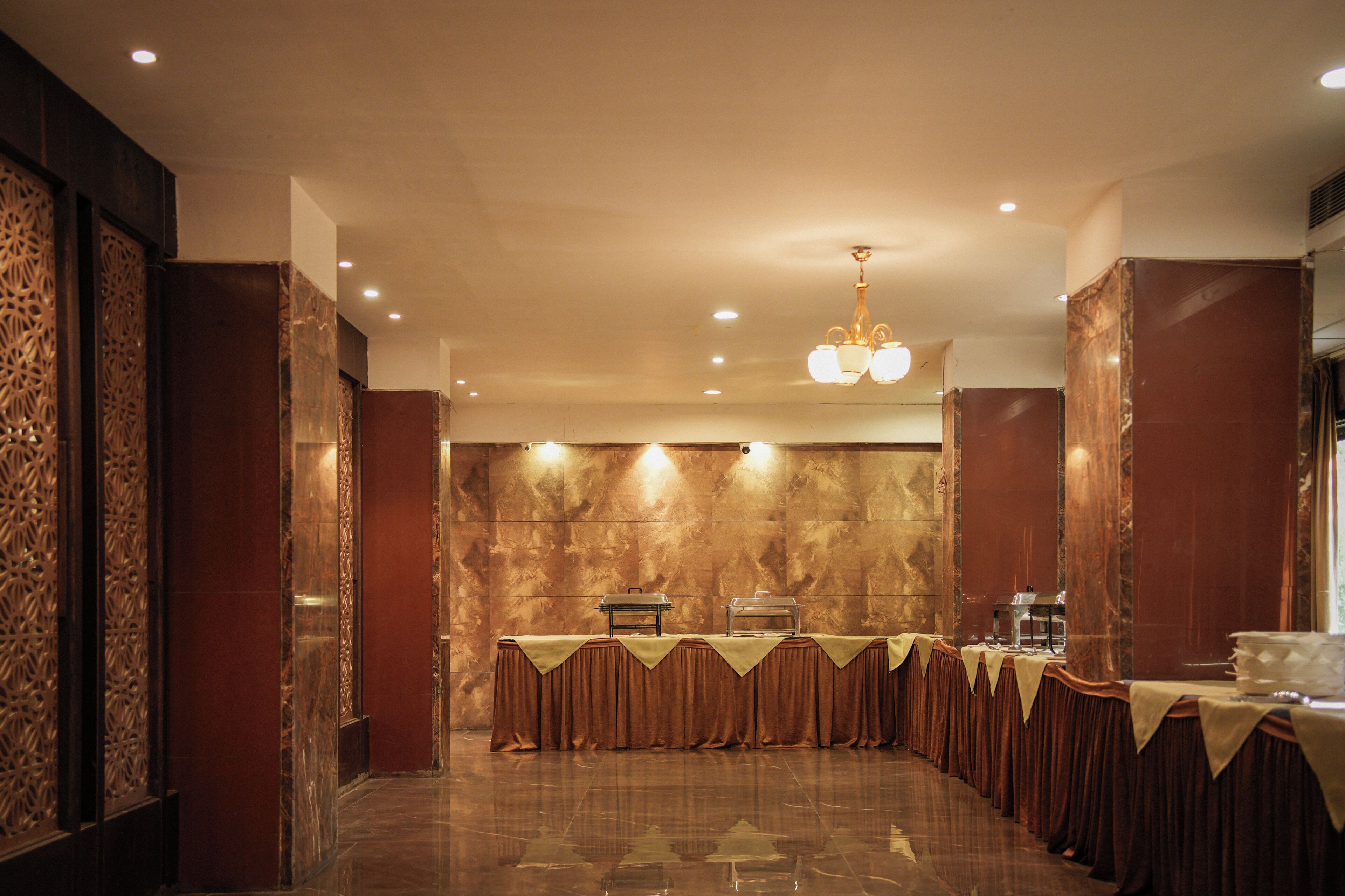 Un salón de banquetes con una larga mesa, paneles decorativos en la pared y una araña.
