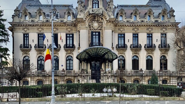 Un edificio imponente y ornamentado con una entrada central, varios balcones y un techo decorativo.
