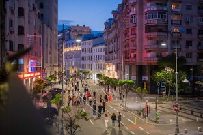 A busy urban street with pedestrians, buildings, and streetlights.