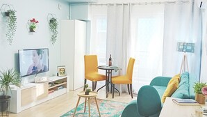Una sala de estar moderna con televisor, sofá, mesa de comedor con sillas y una pequeña mesa de centro.